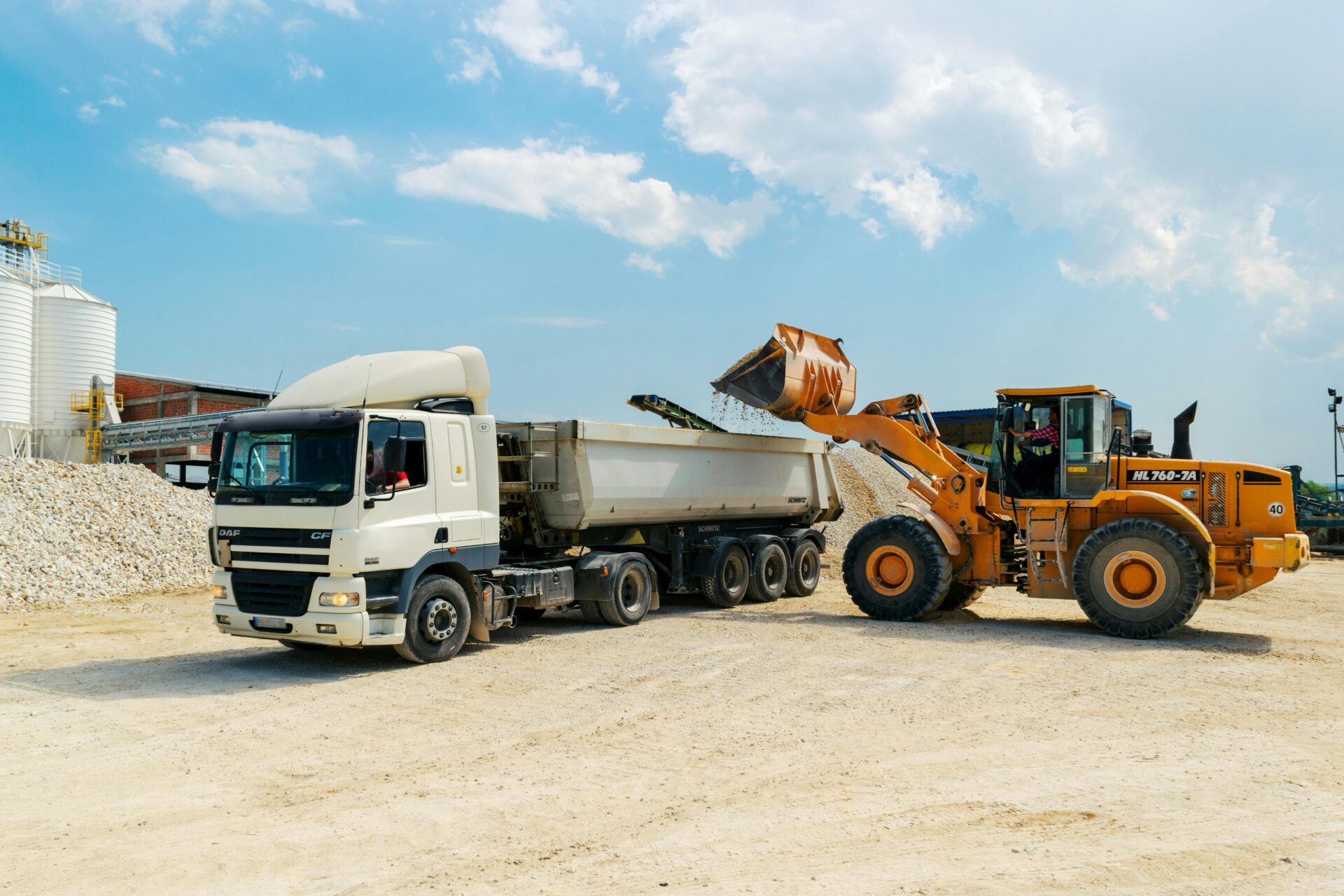 A truck being loaded with gravel at a construction site, illustrating the importance of a trucking business loan for equipment and operational expansion.