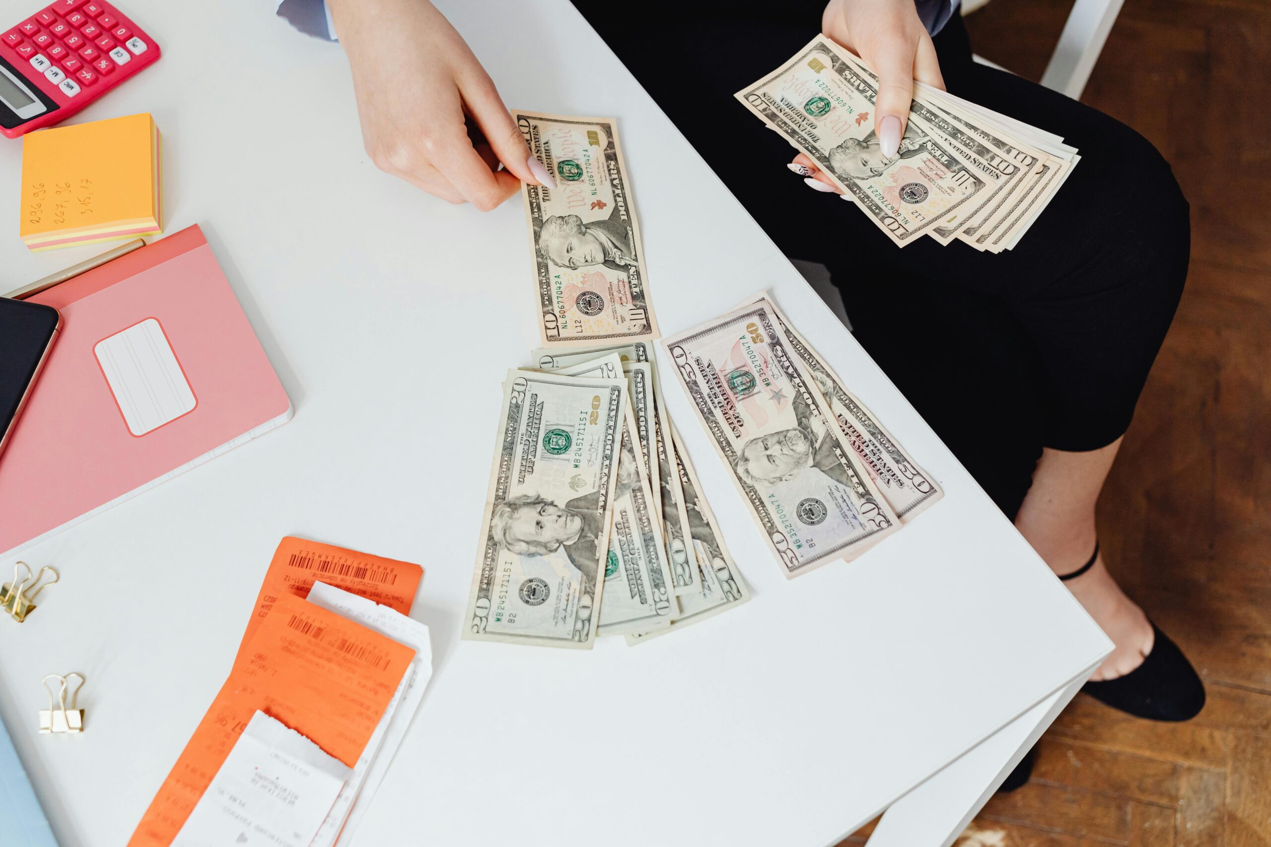 A person counting cash on a desk with receipts and notes, representing a practical financing solution for businesses to manage funds effectively.